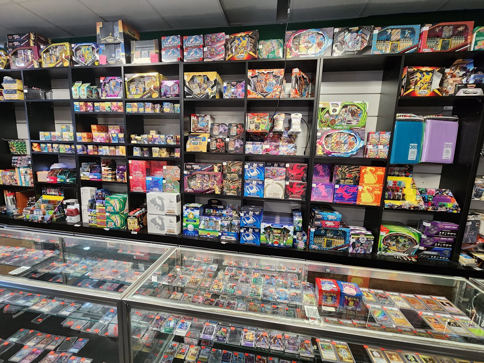 Inside Sage Mantis Game Haven: walls of sealed Pokemon and Magic product above glass cases full of trading card singles